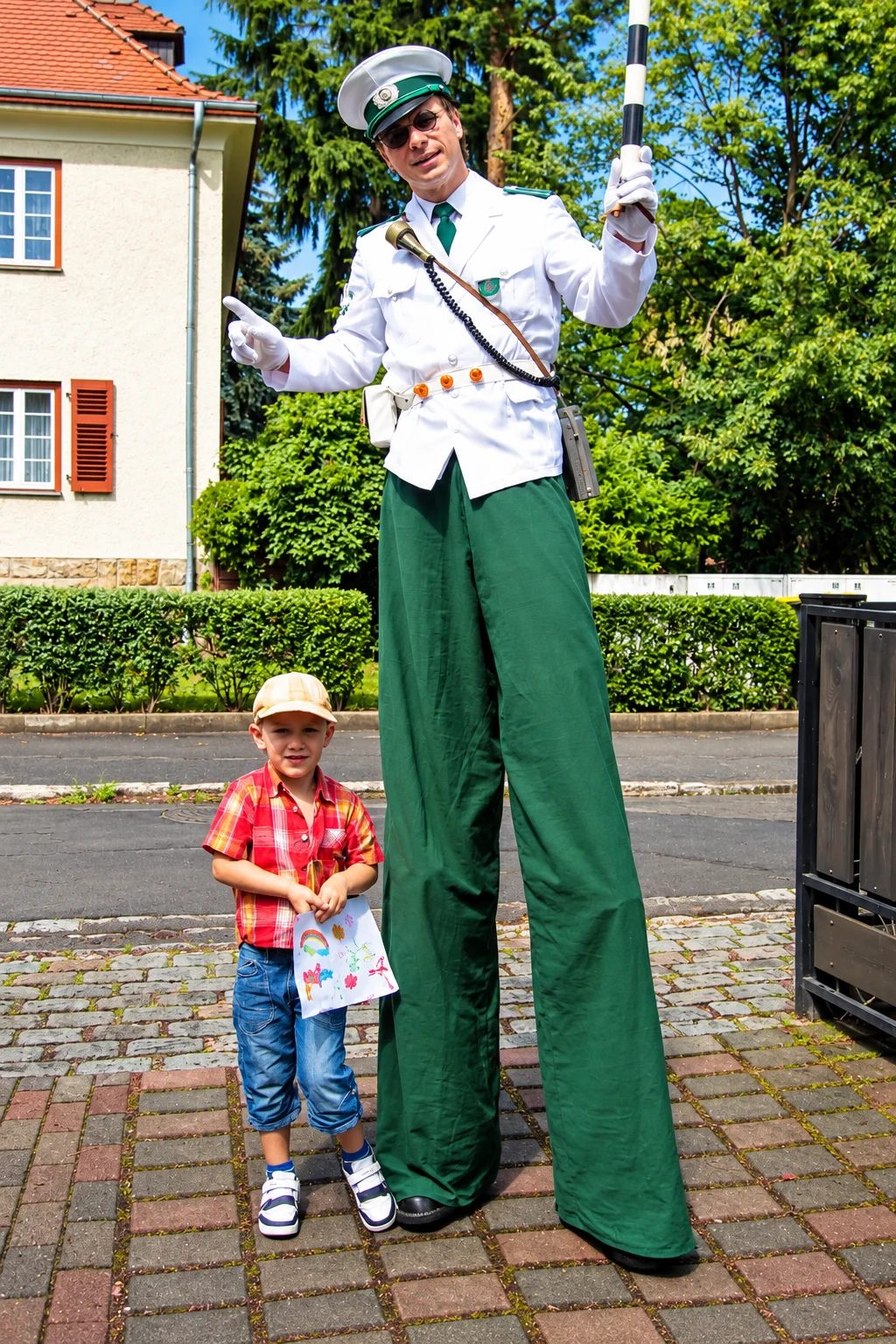 Stelzenkuenstler und Kind im Sonnenschein 1